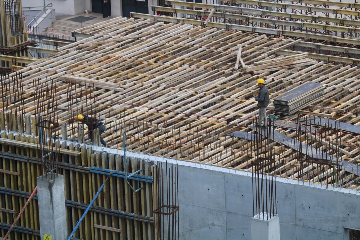 Workers tying reinforcing steel on a construction site under engineering supervision