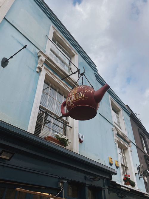 Free Low angle shot of a vintage teapot sign outside a city café, showcasing unique urban decor. Stock Photo