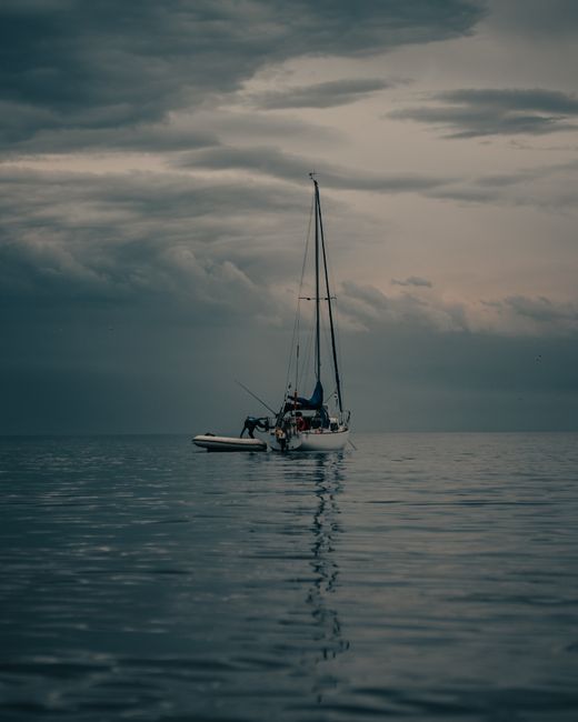 A sailboat peacefully anchored under dramatic clouds in Newcastle, Canada.