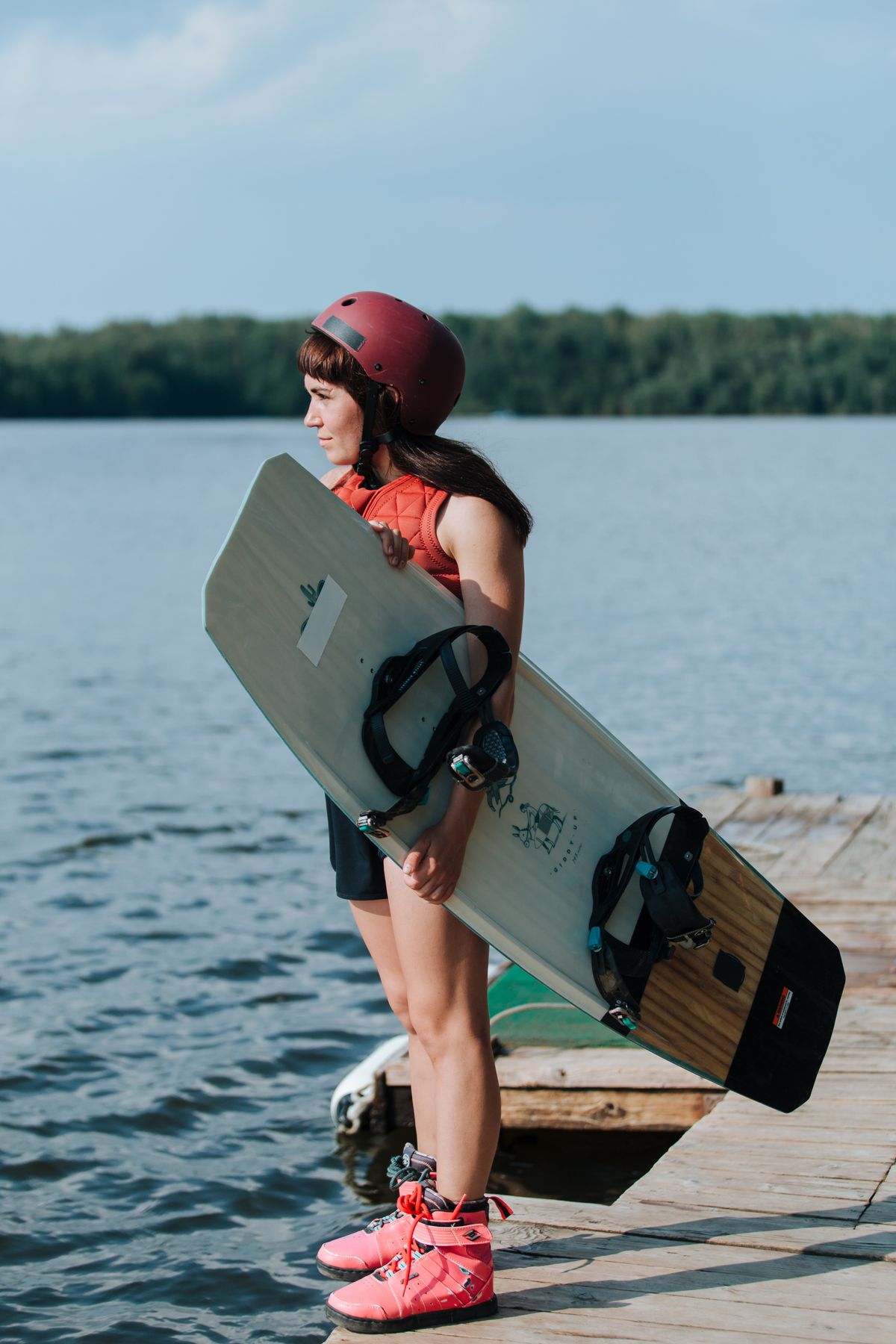 Rider holding a wakeboard on a lakeside dock