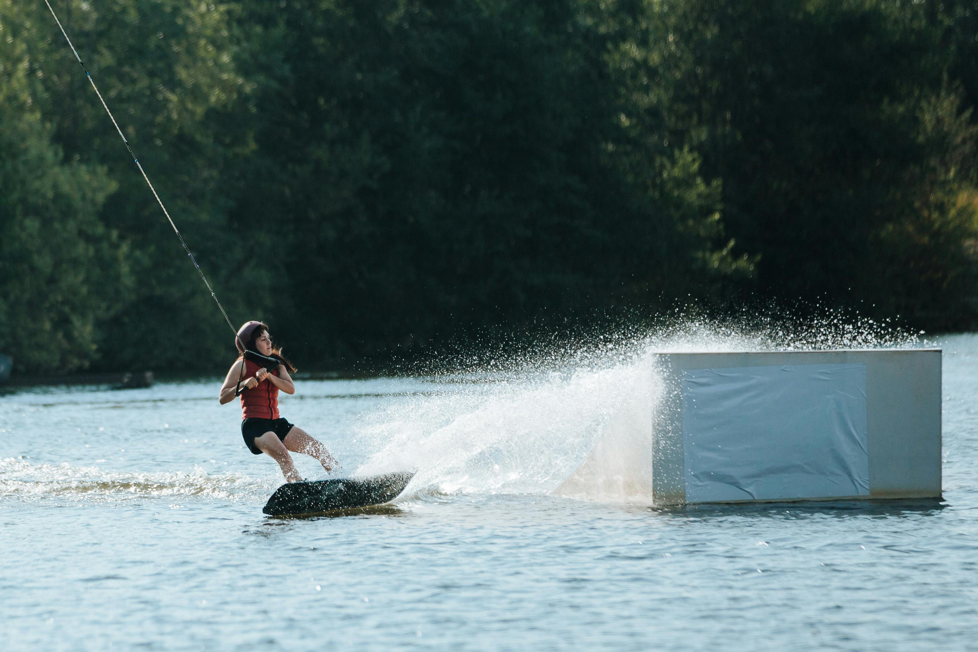 woman wakeboarding near ramp on lake