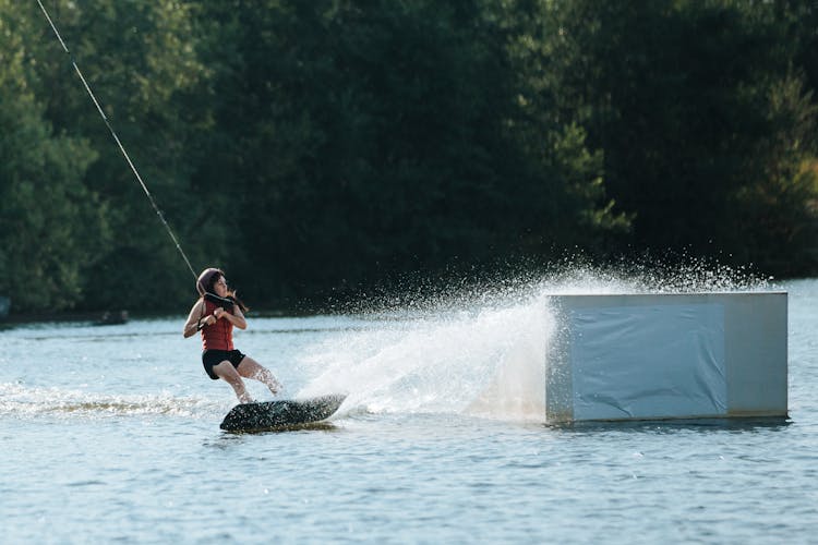 Woman Wakeboarding Near Ramp On Lake