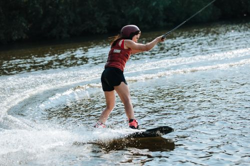 Free A woman skillfully wakeboarding on a sunny lake, showcasing balance and thrill. Stock Photo