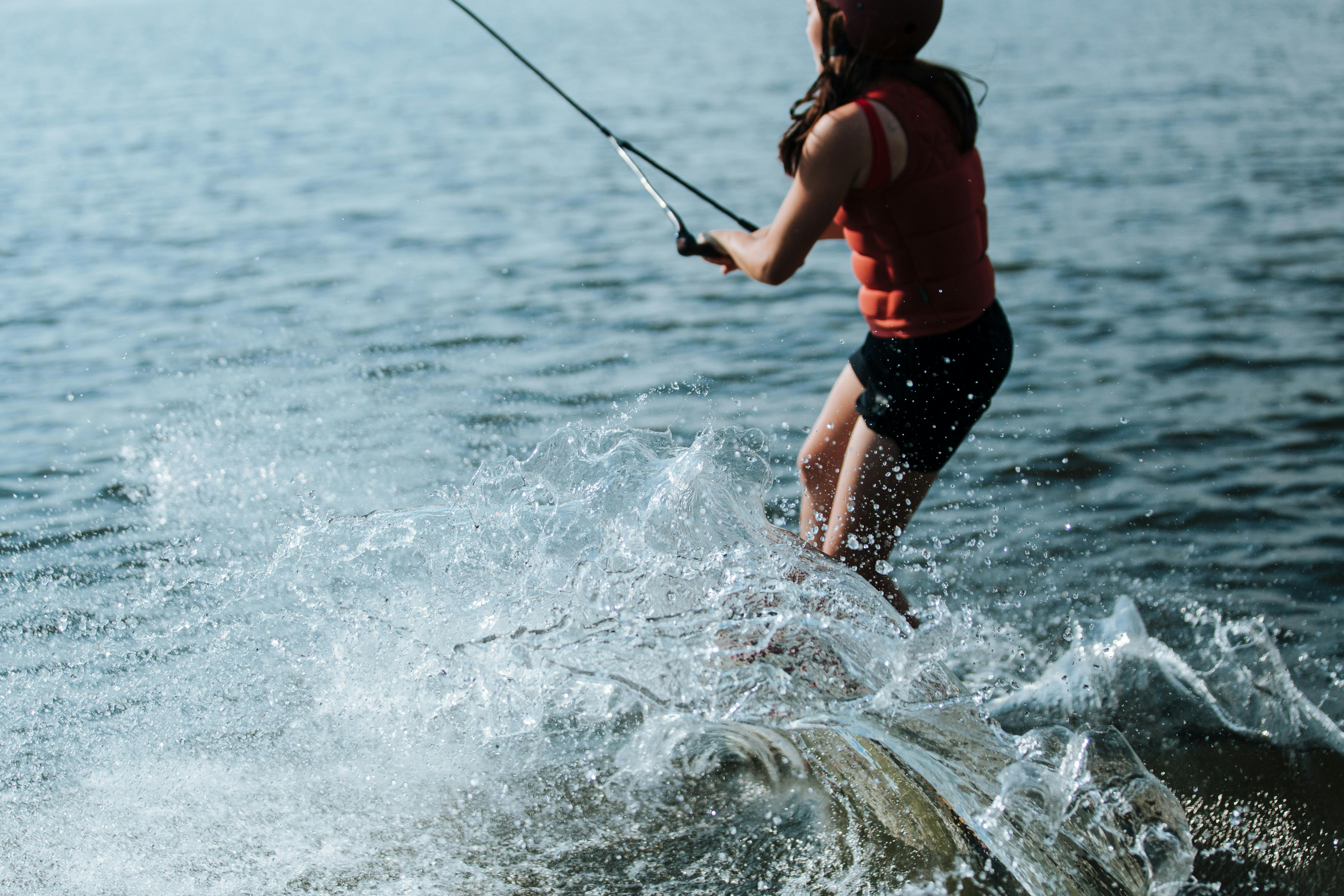 Prescription Goggle Inserts - Woman wakeboarding on a lake with splashing water, showcasing excitement and adventure.