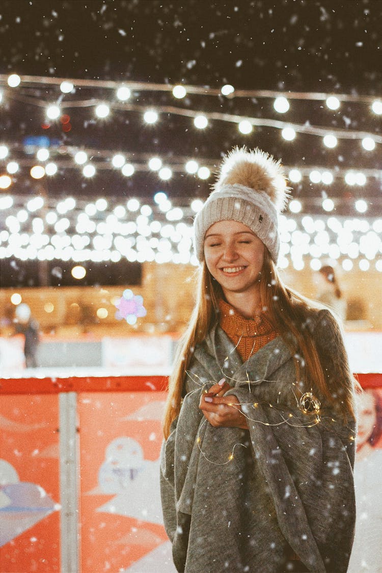 Teenage Girl In Winter Hat And Wrapped In Blanket With LED Lighting