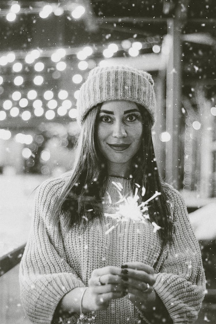 Woman In Winter Hat And Pullover Holding Sparkler In Hands