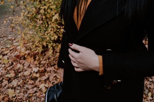 Free Woman with dark coat and painted nails standing near fall leaves in Kherson, Ukraine. Stock Photo
