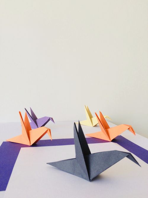Free A collection of colorful origami paper birds artfully arranged on a white background. Stock Photo