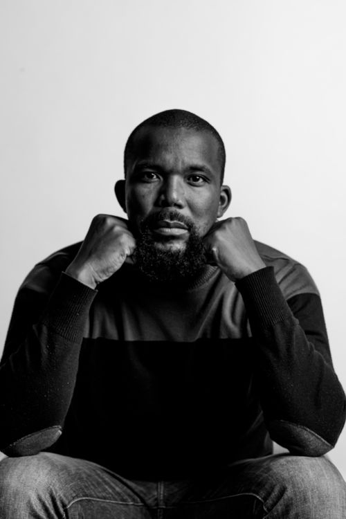 Free A serious black and white studio portrait featuring a bearded man with a shaved head in a pensive pose. Stock Photo