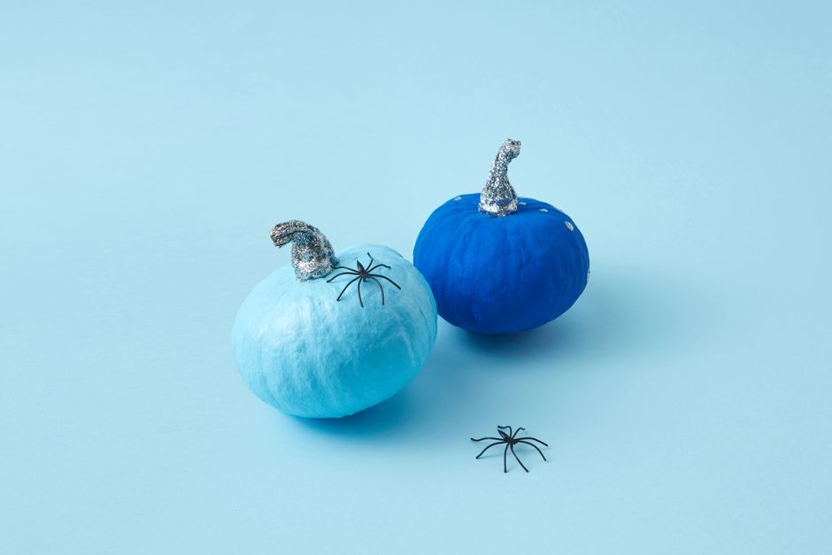 Two blue pumpkins with glitter stems and spiders on a light blue background.