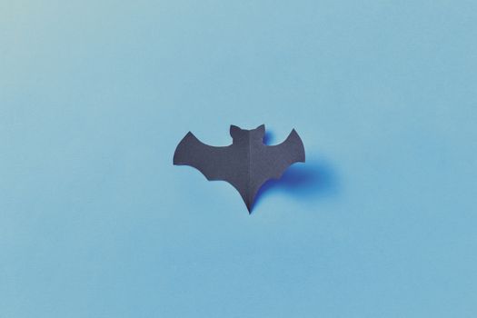 Simple paper bat on a vibrant blue surface, perfect for Halloween decor.