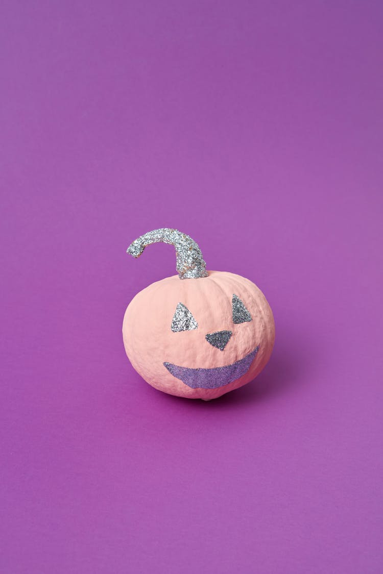 Pumpkin With Face On Purple Surface