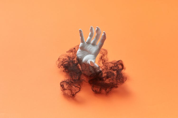 A White Fake Hand Surrounded By Black Hair