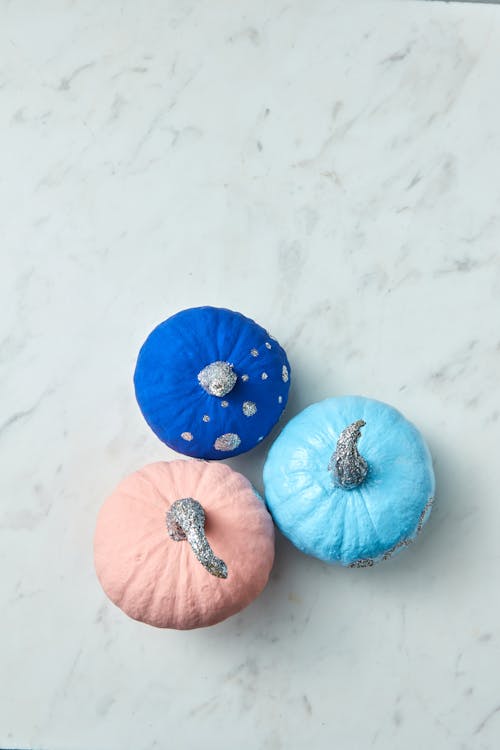 Top View of Colored Mini Pumpkins with Glittery Stems on a Marble Surface