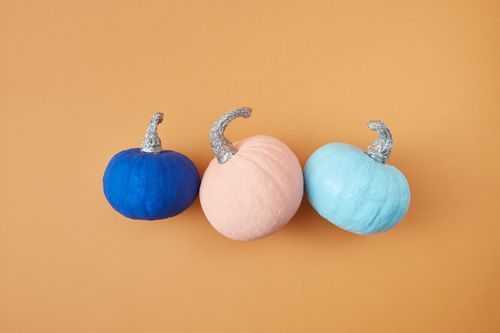 Free Three colorful pumpkins with glitter stems on a warm orange background, perfect for creative fall decor. Stock Photo