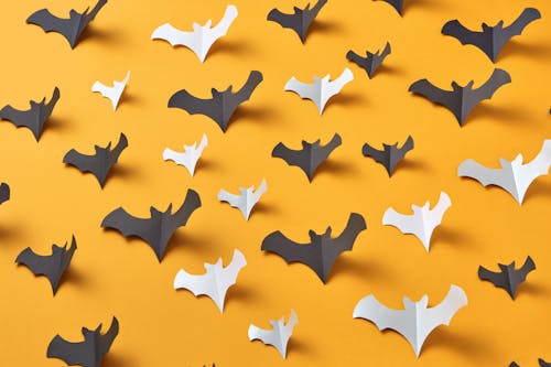 Black and White Bat Shaped Paper Cut Outs on a Yellow Surface