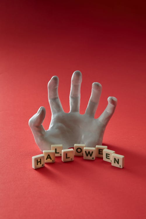 A Fake Hand and Scrabble Tiles with a Halloween Caption