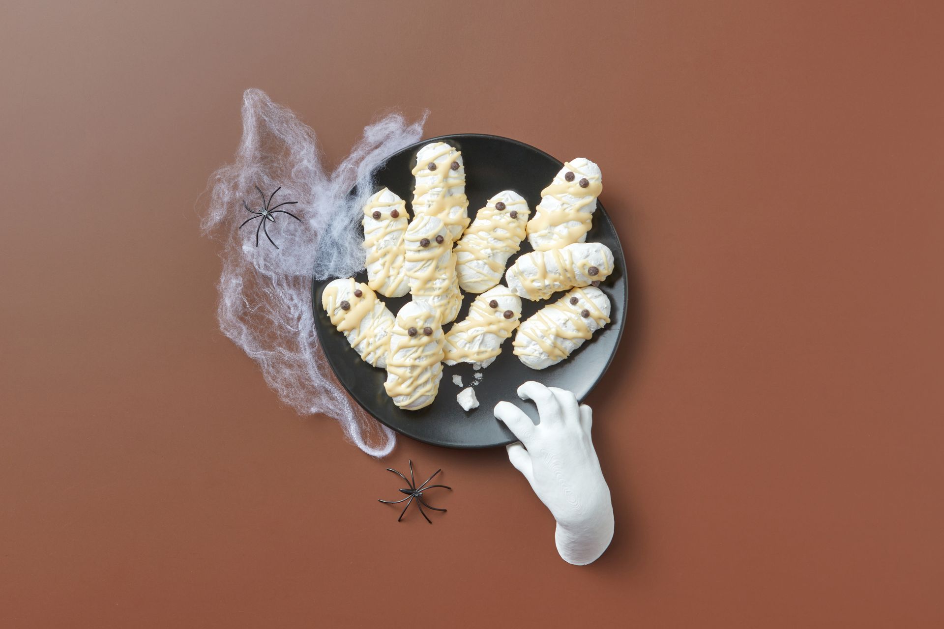 Creative Halloween cookies styled as mummies with spider and cobweb decorations for a festive treat.