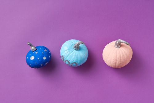 Free Three colorful decorative pumpkins on a purple background, artistic composition. Stock Photo