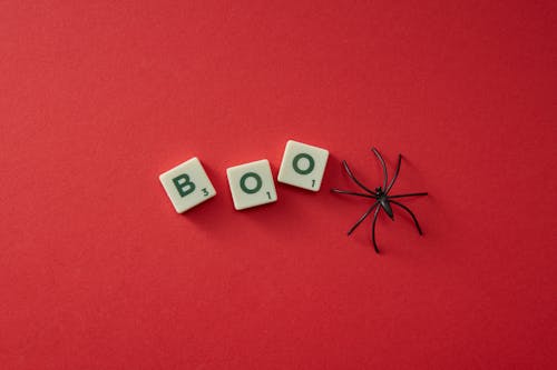 Plastic Scrabble Letters and Plastic Spider on Red Background