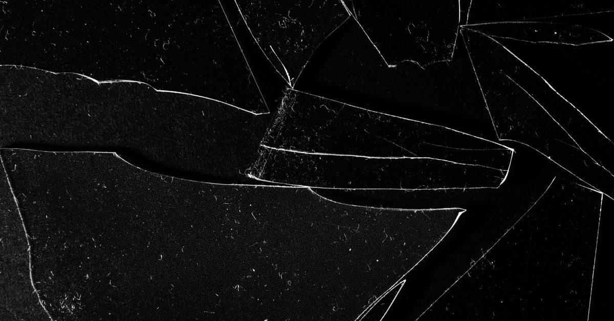 A high-speed photograph of an egg shattering on a black surface, with yolk splashing in a chaotic pattern
