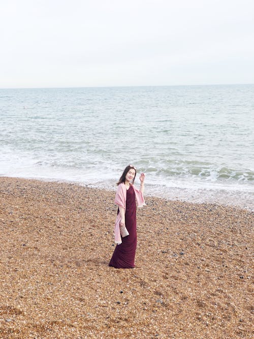 Woman Wearing Maroon Long Dress Near Seashore
