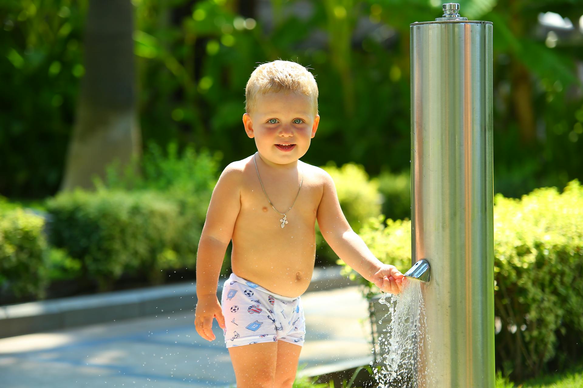 Adorable child having fun at an outdoor water fountain on a sunny day.