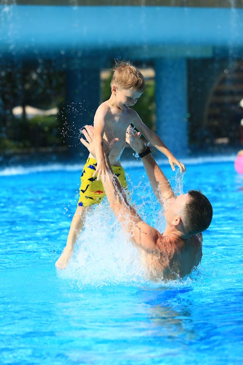 A Man and a Boy Playing in a Swimming Pool