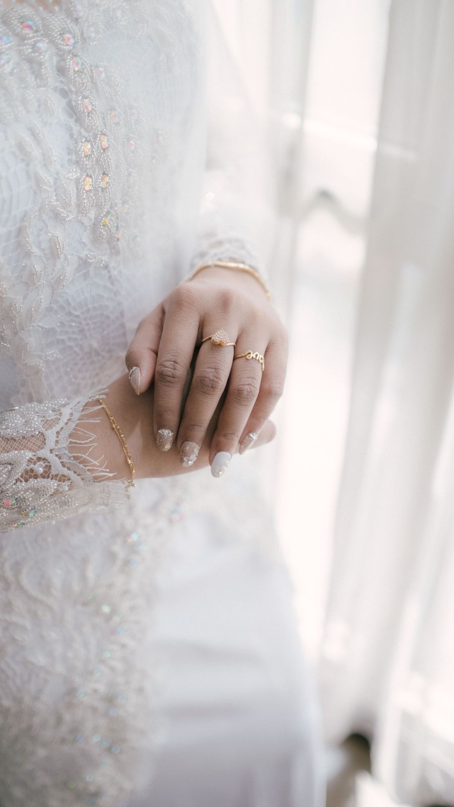 Woman's hands with elegant manicure and jewelry in a lace dress
