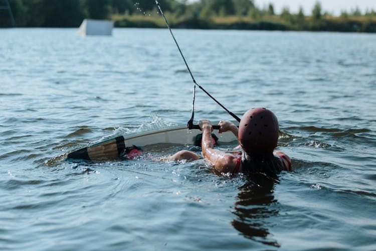 Rear View On Woman In Water With Wakeboard