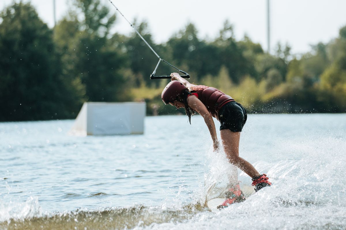 Rider carving across a calm lake behind a boat