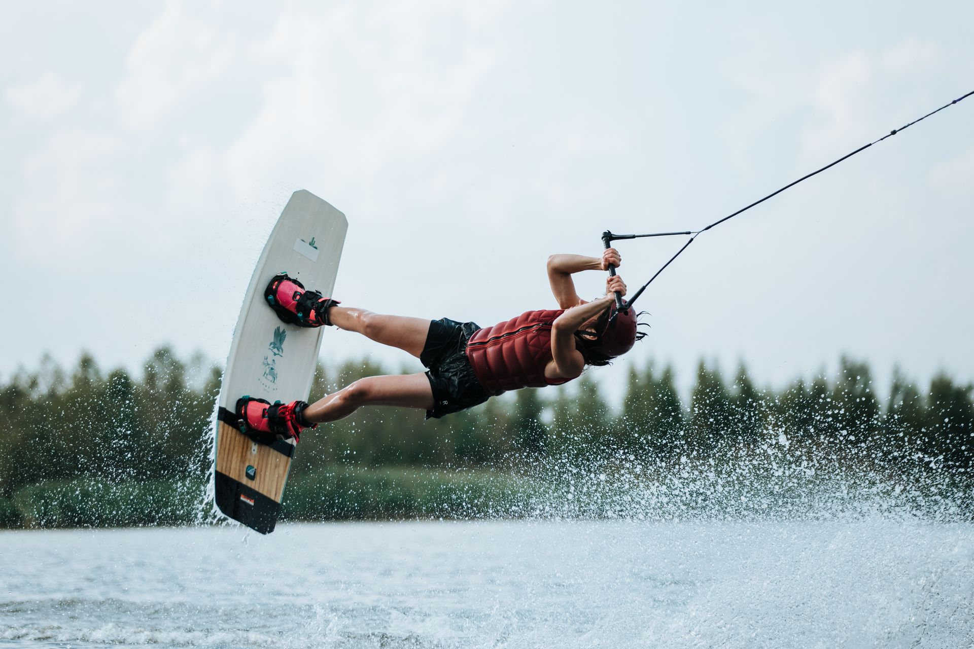 Woman performing an exhilarating wakeboarding trick on a sunny day, showcasing adrenaline and excitement.