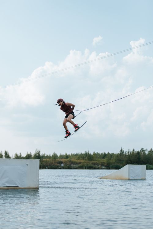 Free Skillful female wakeboarder performs a trick mid-air on a sunny day. Stock Photo