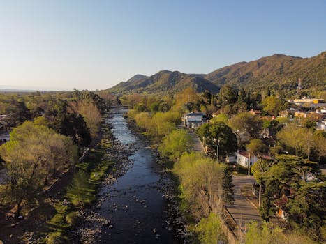 A picturesque aerial view of a river flowing through lush green mountains and a quaint village.