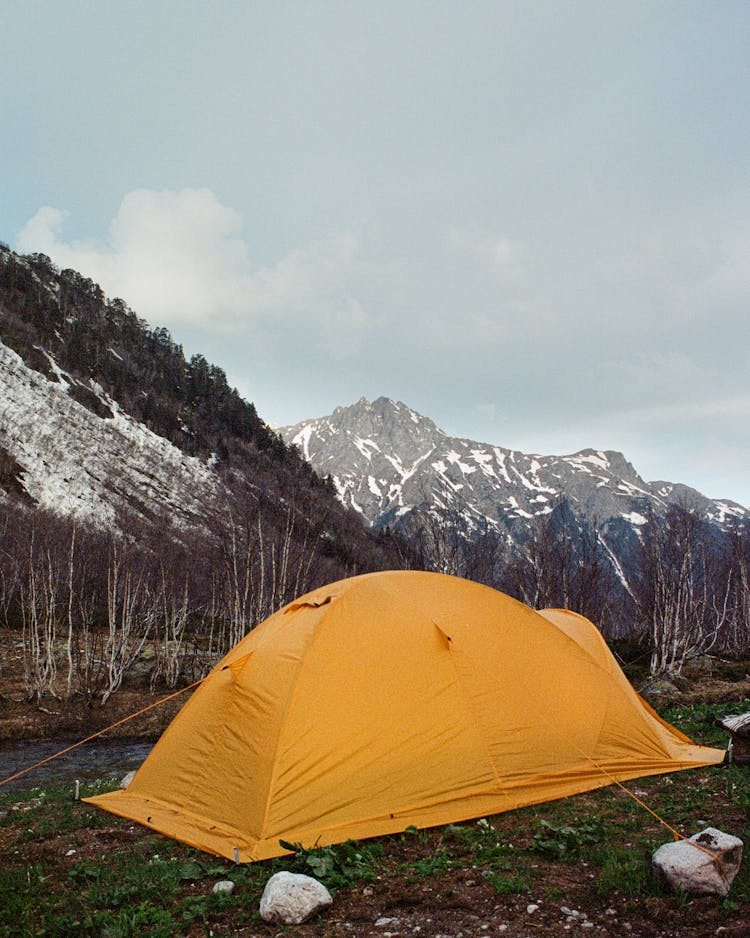 Orange Tent On Green Grass Field Near Snow Covered Mountain