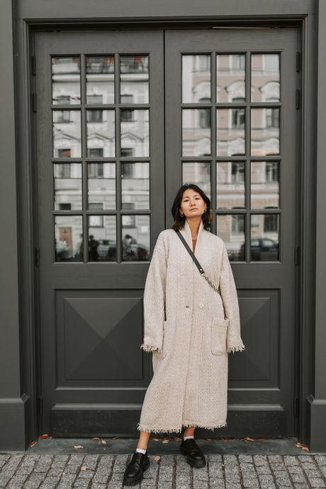Model in a pale long coat against a grey wall — photo by Vlada Karpovich on Pexels