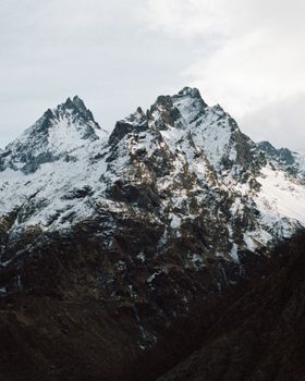 Majestic mountain peaks with patches of snow under a cloudy sky, perfect for nature enthusiasts.