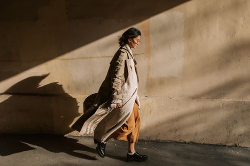 Woman Wearing Trench Coat Walking Near a Wall · Free Stock Photo