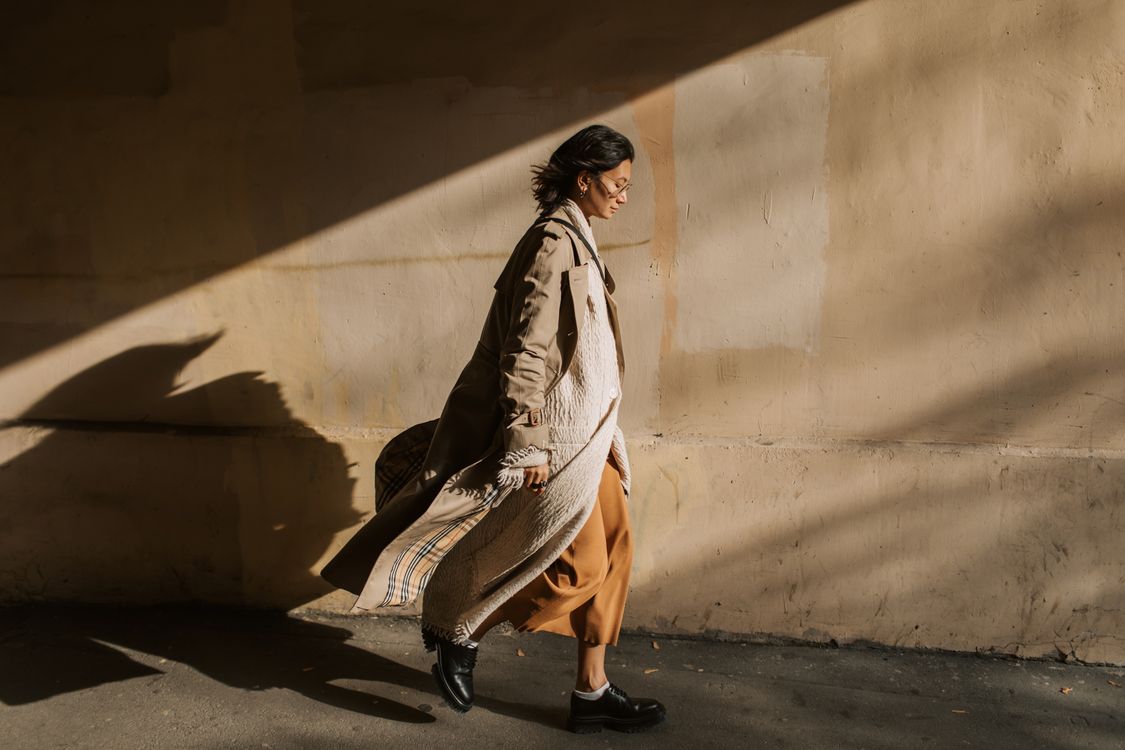 Woman In A Beige Trench Coat Walking Outdoors In Golden Light