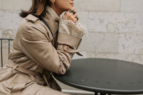 Free Woman Wearing Trench Coat Sitting at a Table Stock Photo