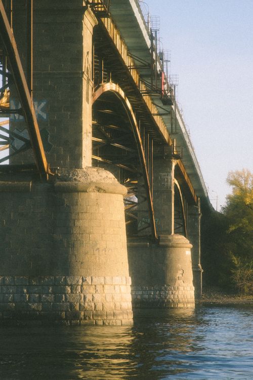 Free A vintage-style photo of a concrete bridge with arches over a river at sunset. Stock Photo