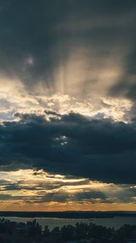 A captivating sunset scene with sunbeams piercing through dramatic clouds over a serene landscape.