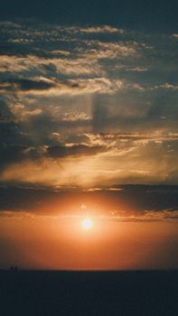 Capture the breathtaking beauty of a golden sunset with dramatic clouds on the horizon.