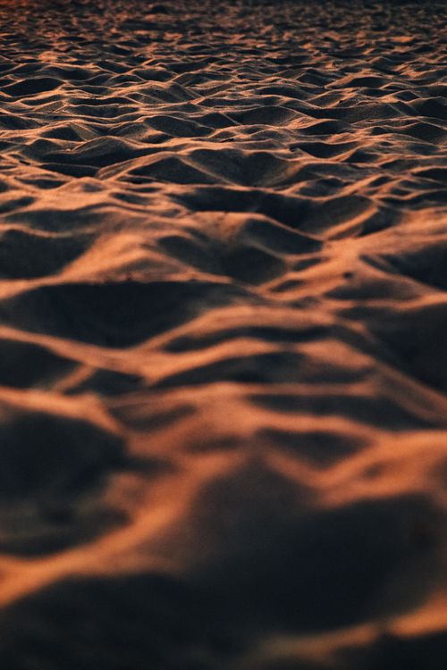 Free Capture of rippled sand dunes at sunset, showcasing desert's rich texture and warm colors. Stock Photo