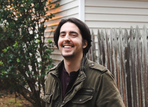 Free Man Wearing Jacket Standing Beside a Wooden Fence Stock Photo