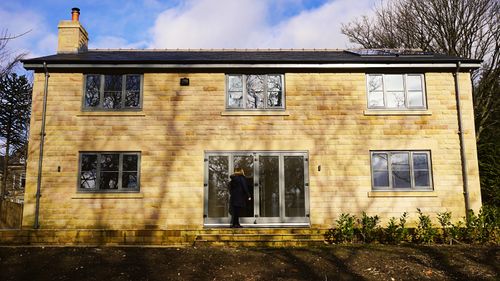 Free Contemporary brick house exterior with glass windows and a woman at the door in the UK. Stock Photo