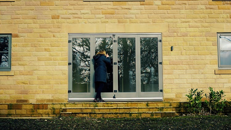 Woman Looking Through A Glass Door