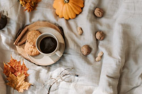 Free Warm autumn scene featuring coffee, cookies, walnuts, and pumpkin on a cozy cloth background. Stock Photo