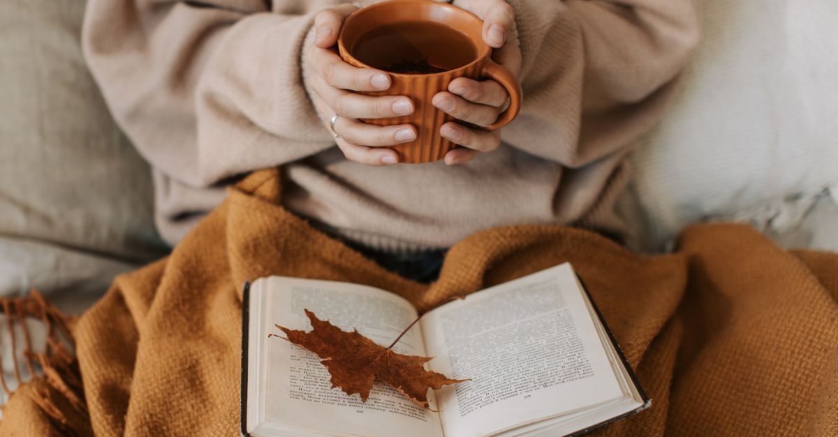 A person sitting peacefully in a garden in Ho, reading a book with a cup of tea beside them