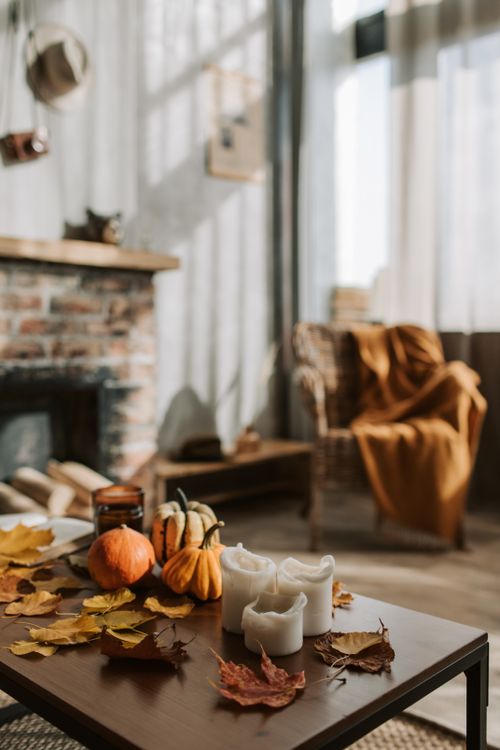Free Warm and inviting living room with pumpkins and candles on a wooden table, perfect for cozy autumn nights. Stock Photo